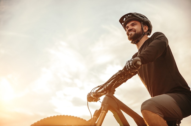 Ciclista maschio sorridente fiducioso che guida mountain bike moderna