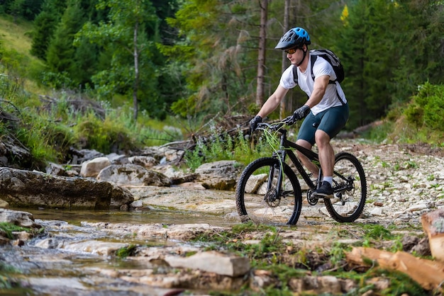 Ciclista professionista di mountain bike in sella a un sentiero sull'acqua nella foresta Sport d'avventura all'aperto