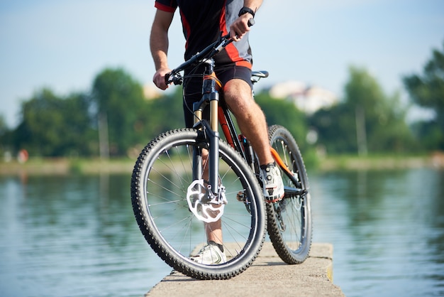 ciclista vicino alla bici sul molo vicino al lago della città