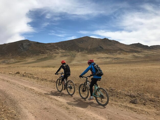 Ciclistas en el campo conducendo por el camino llano