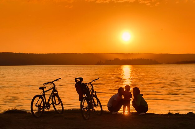 Ciclisti al fiume al tramonto