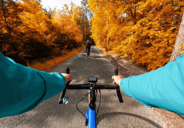 Ciclisti che guidano nella foresta variopinta di autunno