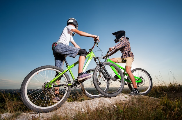 Ciclisti con le mountain bike sulla collina sotto il cielo blu