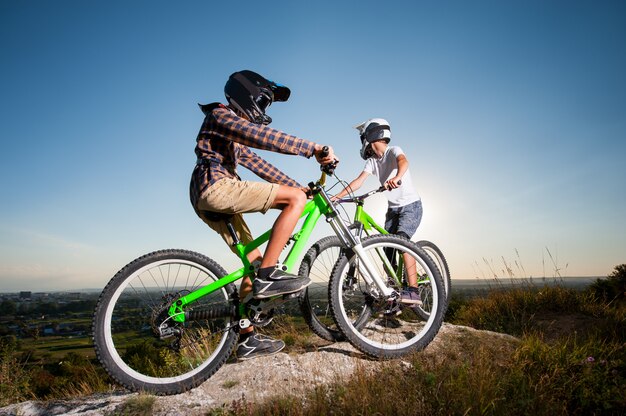 Ciclisti con le mountain bike sulla collina sotto il cielo blu