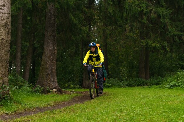 Cicloturista attrezzato percorre un sentiero in un bosco di abeti rossi