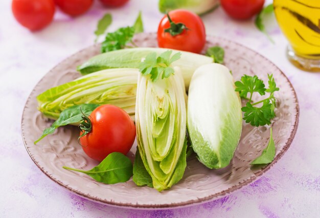 Cicoria fresca e sana (witloof) Insalata e pomodoro su un piatto. Menu dietetico. Cibo salutare.