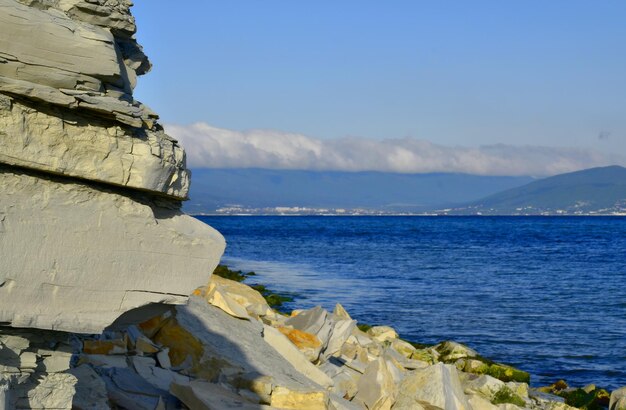 Cielo azzurro alte montagne coperte di nuvole ai piedi del mare infinito costa rocciosa Mar Nero Cape Dolfin Novorossiysk Russia