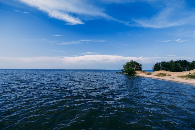 Cielo azzurro e limpido con onde sull'acqua del mare e una spiaggia sabbiosa il giorno d'estate