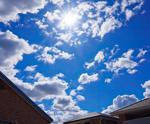 Cielo blu con nuvole bianche e sole sopra un edificio residenziale in estate Foto di alta qualità