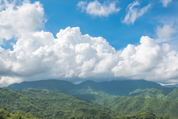 Cielo blu con nuvole gonfie e paesaggio di montagne.