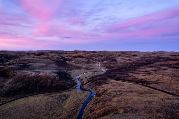 Cielo colorato sopra il campo di lava del muschio con il fiume che scorre negli altopiani islandesi sul deserto al tramonto in Islanda