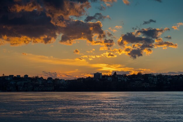 Cielo con nuvola sul lago coperto di ghiaccio durante il disgelo riflesso del tramonto sul ghiaccio