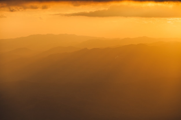 Cielo dorato con la luce del sole e le montagne nel tramonto.