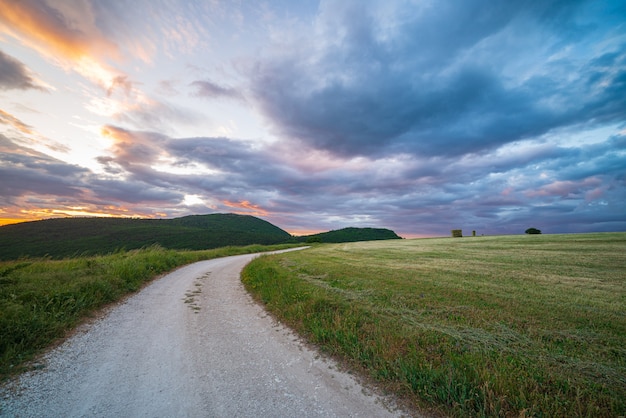 Cielo drammatico di tramonto sopra la strada campestre nella regione Marche, Italy