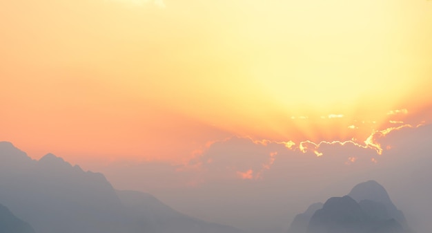 Cielo luminoso al tramonto o all'alba con montagne nebbiose