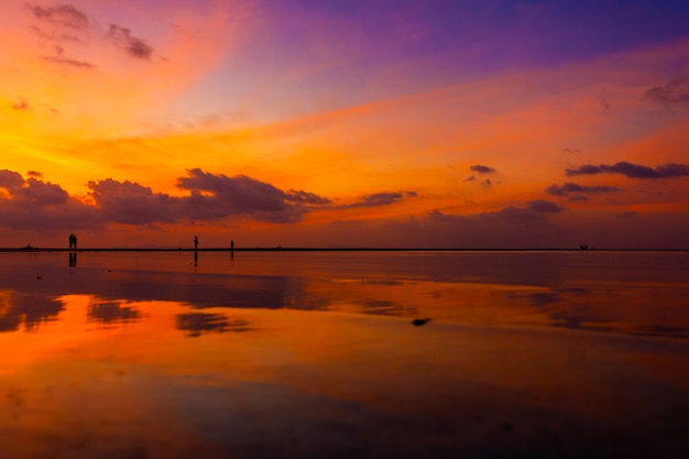 Cielo luminoso bruciante durante il tramonto su una spiaggia tropicale. Tramonto durante l'esodo, la forza della gente che cammina sull'acqua