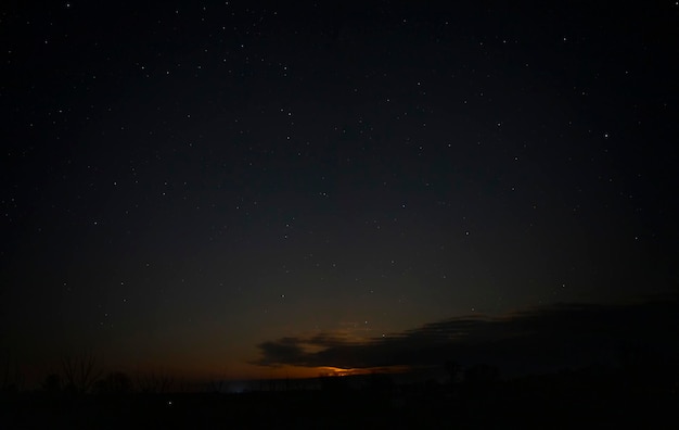 Cielo notturno arancione con stelle e nuvole