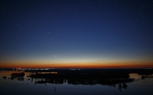 Cielo notturno con le stelle sopra il fiume durante l'alluvione primaverile