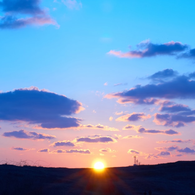 Cielo romantico con sole, bellissime nuvole blu, rosse e gialle