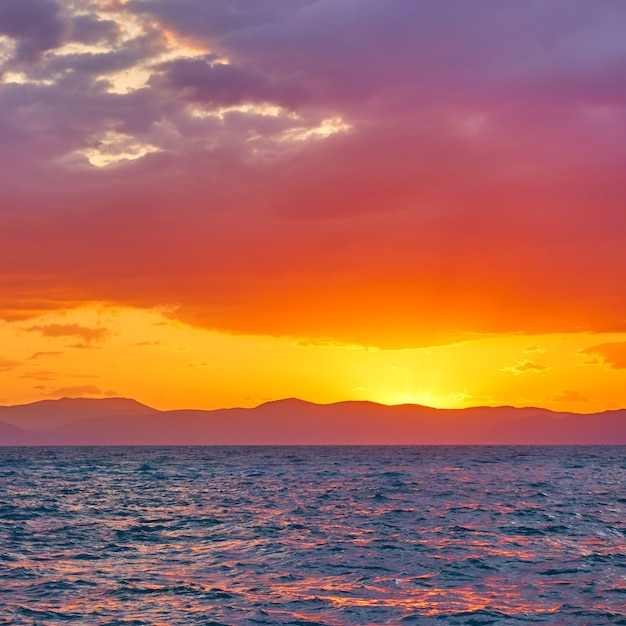 Cielo rosso giallo brillante con nuvole in alto sul mare al tramonto - Paesaggio colorato - vista sul mare