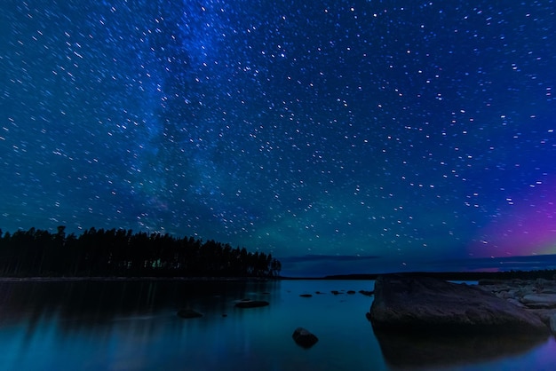 Cielo stellato con costellazioni galassie via lattea e molte stelle sopra l'acqua del fiume con pietre