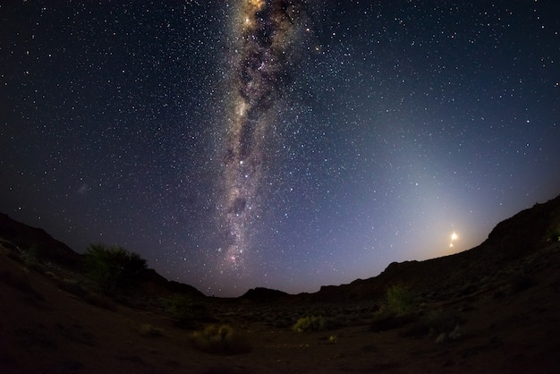 Cielo stellato e arco della Via Lattea con luna crescente, catturato dal deserto del Namib in Namibia, Africa.