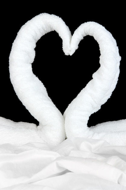Cigni fatti da asciugamani sul letto su sfondo nero