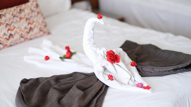 Cigno asciugamano bianco con fiori sul letto in hotel