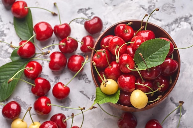 Ciliege rosse e gialle mature in ciotola su fondo grigio