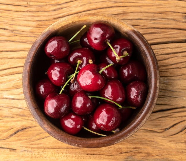 Ciliege rosse su una ciotola sopra il tavolo di legno