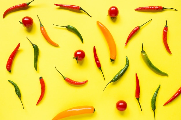 Ciliegia assortita del pomodoro del peperoncino su fondo luminoso giallo