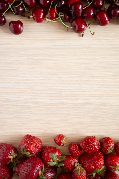 Ciliegia e fragola su un legno bianco