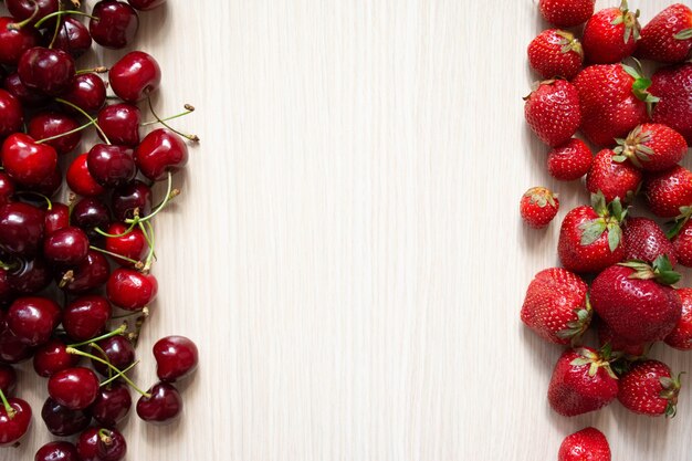 Ciliegia e fragola su un legno bianco