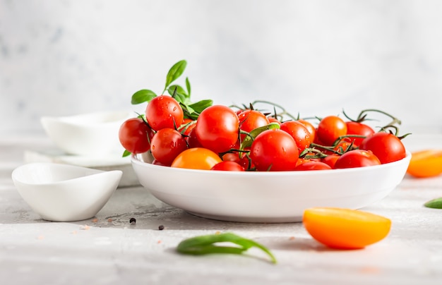 Ciliegia rossa e pomodori gialli con spinaci baby sul piatto bianco