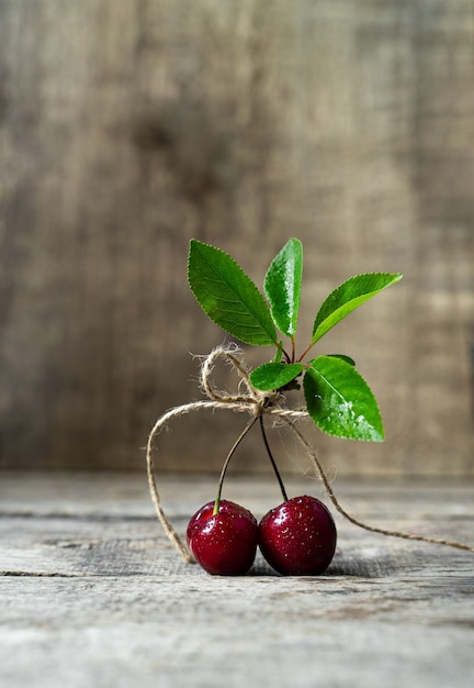 Ciliegie dolci mature e foglie verdi sulla tavola di legno