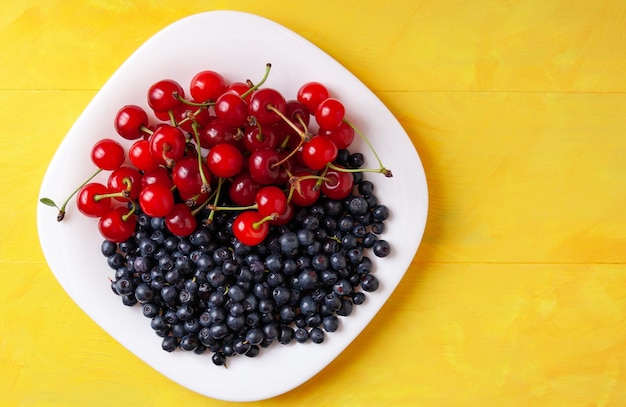 Ciliegie e mirtilli su un piatto frutti di stagione estivi ricchi di vitamine per una corretta alimentazione