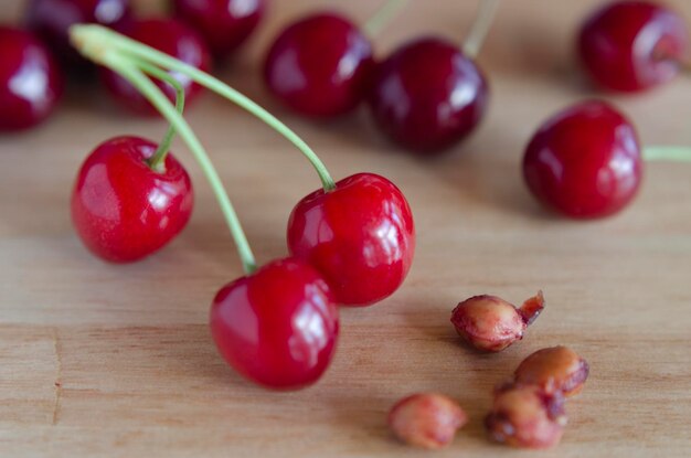 ciliegie rosse brillanti su un tavolo di legno viste da vicino con pozzi di ciliegie sul lato