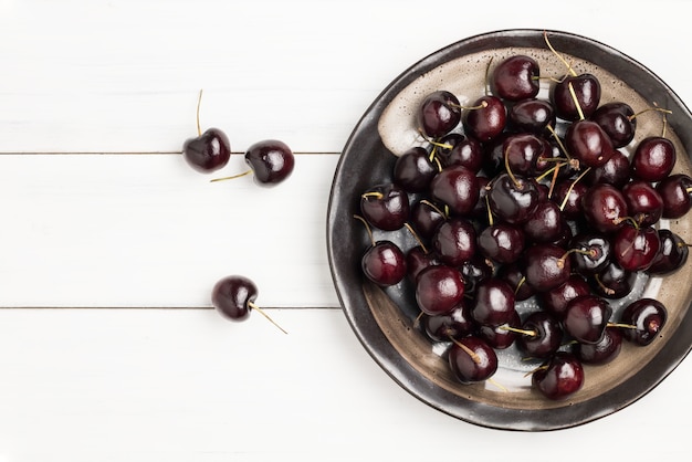 Ciliegie rosse e nere mature fresche in piatto di ceramica nero