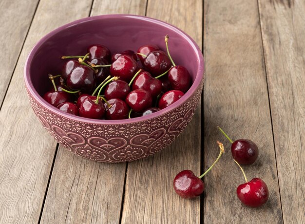 Ciliegie rosse su una ciotola su un tavolo di legno.