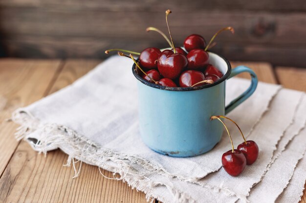 Ciliegie succose fresche in vecchia tazza arrugginita