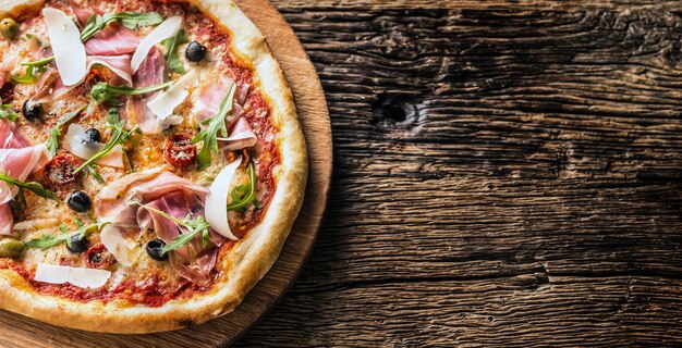 Cima della pizza italiana vista sul piatto di legno e tavola rotonda.