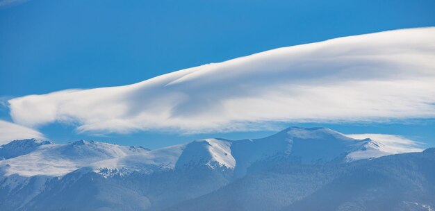 cime innevate con foreste di conifere e nuvole nel cielo blu