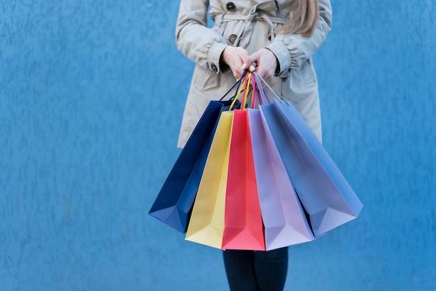 Cinque borse colorate per lo shopping in una mano femminile.