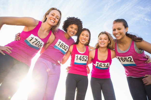 Cinque corridori sorridenti che sostengono la maratona del cancro al seno