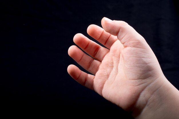 Cinque dita di una mano di un bambino parzialmente visibili su sfondo nero