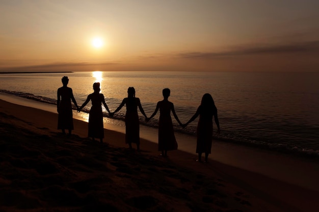 Cinque donne nere si tengono per mano sulla spiaggia all'alba