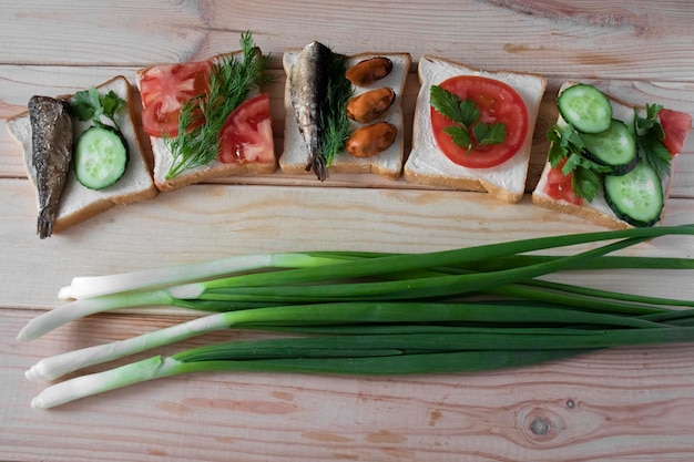 Cinque panini con verdure di frutti di mare e cipolle verdi su uno sfondo di legno da vicino