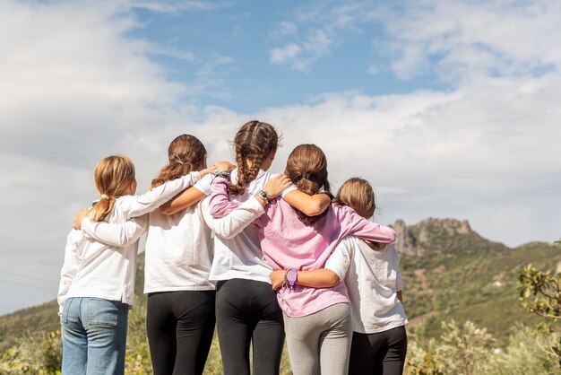 Cinque ragazze amiche accovacciate e che fissano l'orizzonte in mezzo alla natura l'unità dell'amicizia