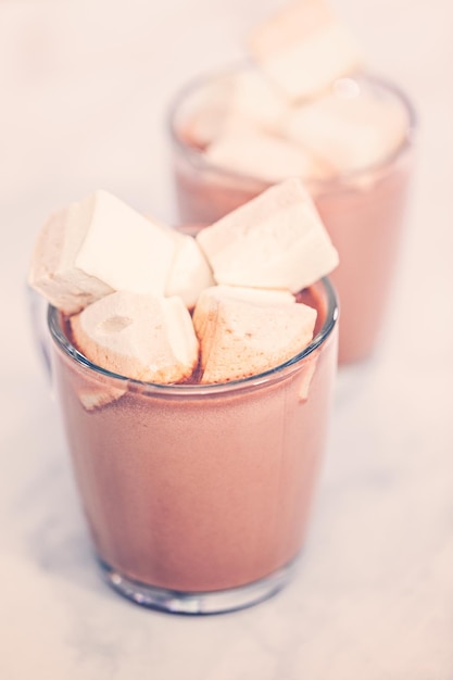 Cioccolata calda americana condita con grande marshmallow in tazza di vetro.