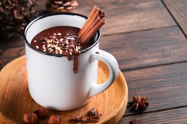 Cioccolata calda Cioccolata calda piccante fatta in casa con nocciola tritata alla cannella in tazza smaltata su fondo di legno vecchio Accoglienti vacanze stagionali